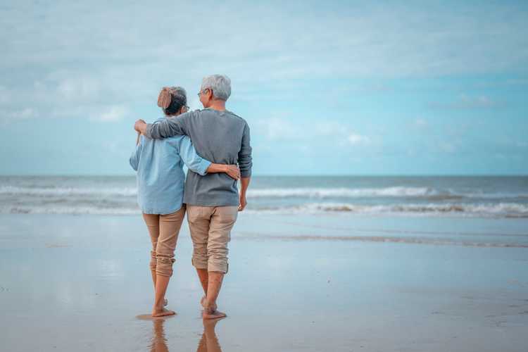 Senior couples walking on the beach plan life insurance retirement in mind.